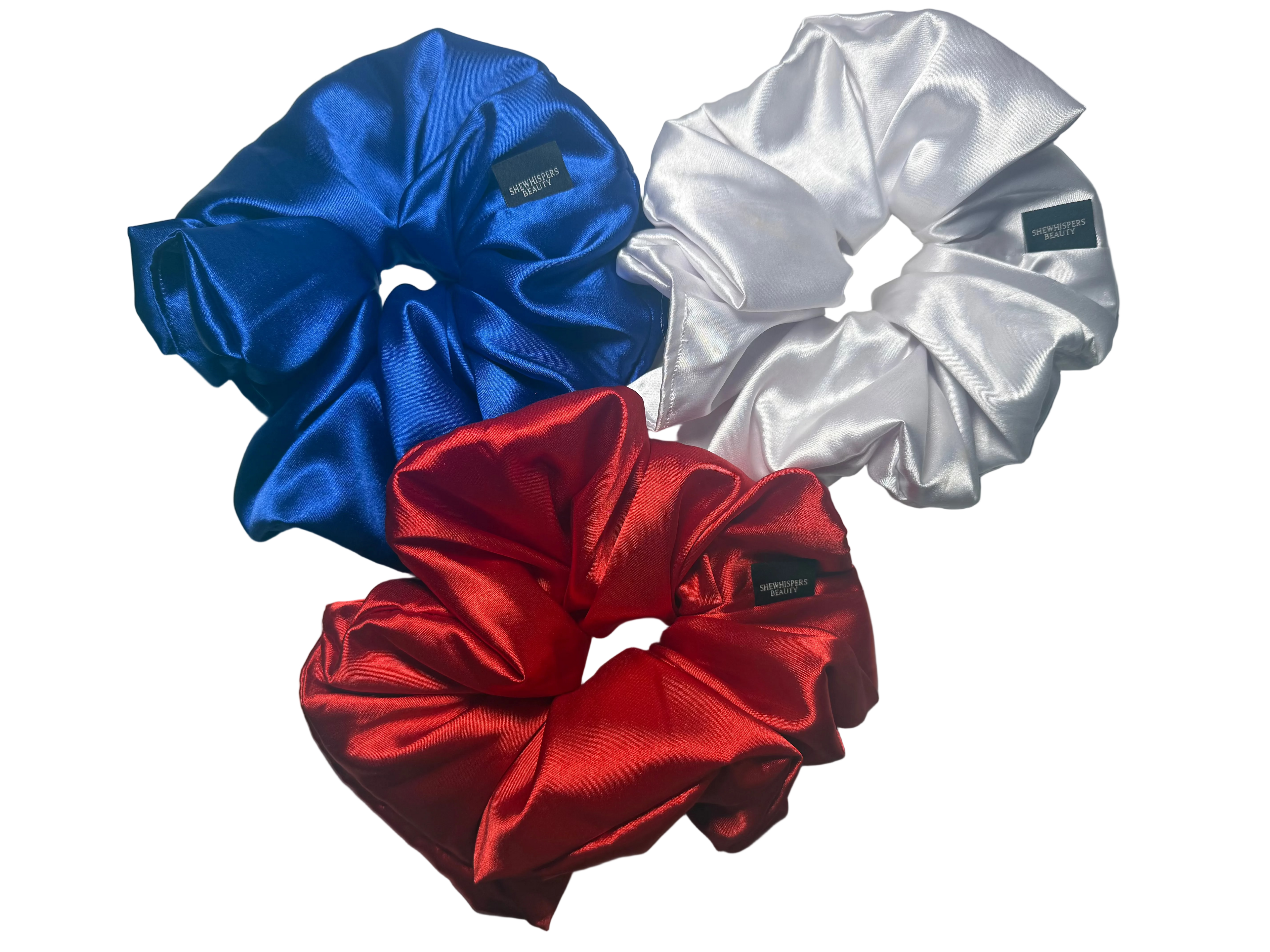 Three satin scrunchies in blue, red, and white on a white background